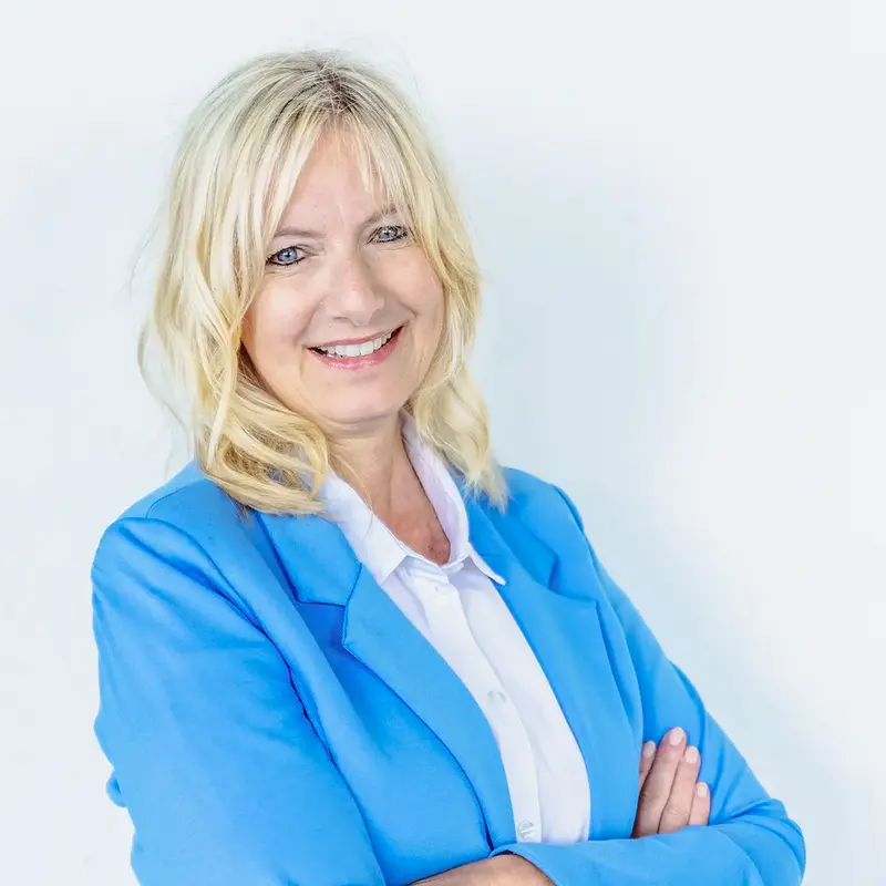 Eine lächelnde Frau in einem blauen Blazer steht als Stadtratskandidatin für die Kommunalwahl 2026 in Landshut bereit.